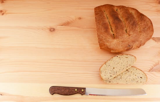 Fresh loaf of bread, cut slices and bread knife form a border with copy space