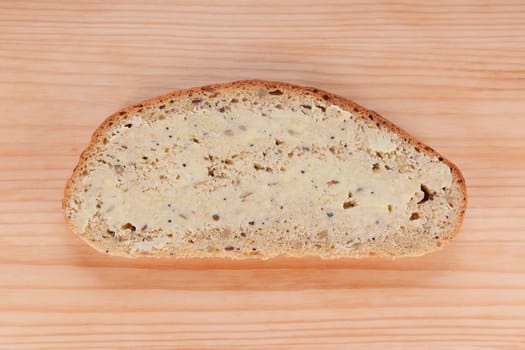 Slice of buttered freshly baked bread on a wooden table