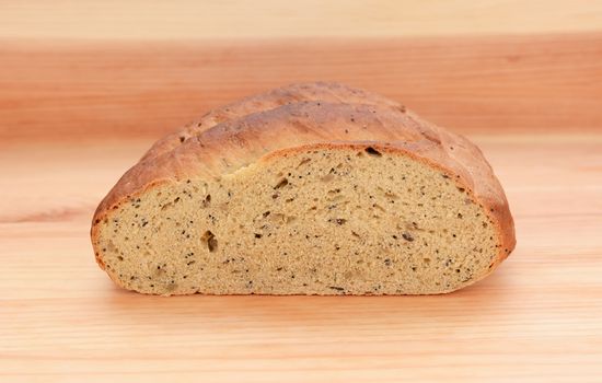 Cross section of multi seed malted bread on a wooden table, showing texture of the loaf
