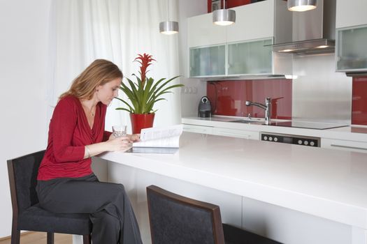 young beautiful woman sitting in modern kitchen interior
