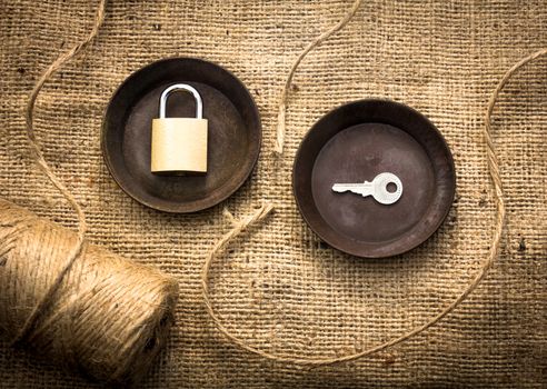 A padlock with its key on two metal plates surrounded by a broken rope