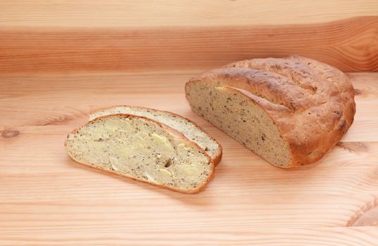 Buttered slice of bread with the remaining loaf on a wooden background