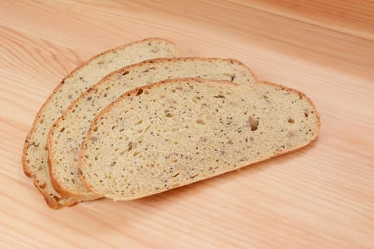 Three slices of multi seed malted bread on a pine wood table