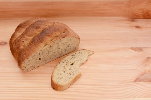 Half-eaten loaf of bread on a wooden table with a cut slice with a bite taken from it