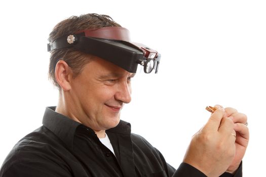 A jeweler examining a golden ring with magnifying glass