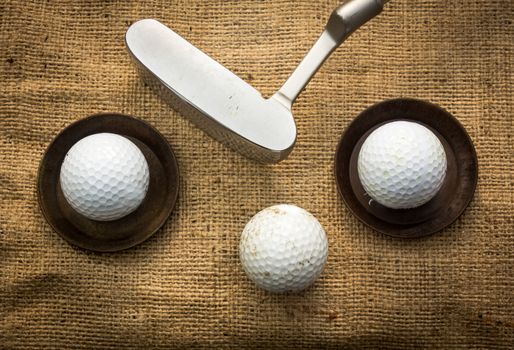 Golf balls lying on metal plates next to a putter