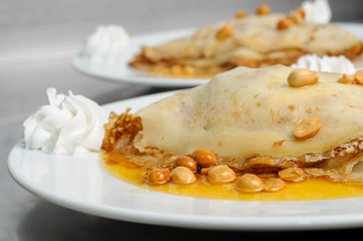 pancake crepe with peanuts and honey decorated with whipped cream