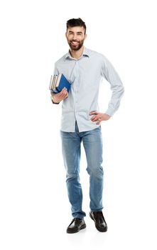 Young bearded smiling man with books in hand on white background