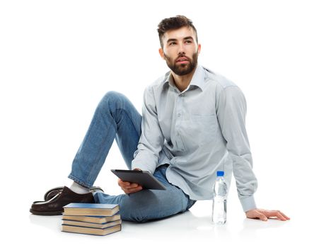 Young bearded man holding a tablet with books and a bottle of water sitting on a white background