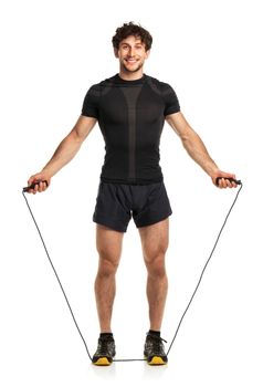 Athletic attractive man jumping on a rope on the white background