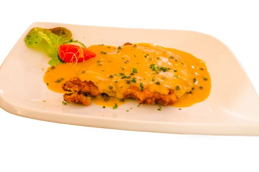 Wiener schnitzel with sauce and tomatoes on a white plate