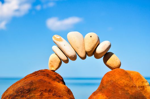 Curve of pebbles between of the red stones on the seashore