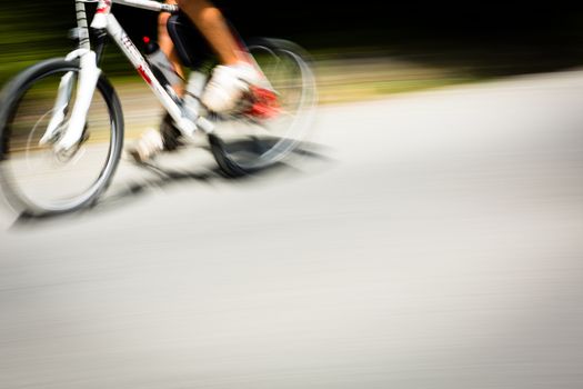 Cyclist on a road bike going fast (motion blur technique is used to convey movement; colour toned image)