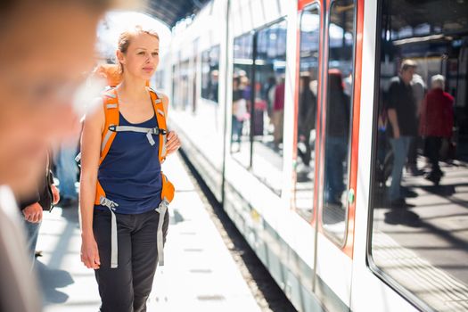 Pretty, young woman in a trainstation, waiting for her train, boarding a train (color toned image)