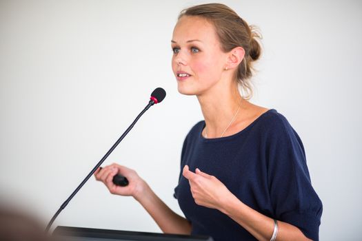 Pretty, young business woman giving a presentation in a conference/meeting setting (shallow DOF; color toned image)