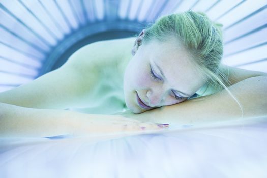 Pretty young woman tanning her skin in a modern solarium