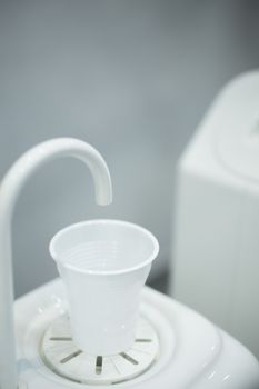 Dentist's water cup tap pip filler in dental clinic in artistic blue purple white tones. 