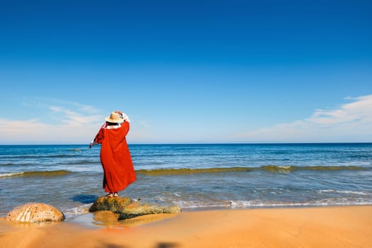 Woman in red dress on the seashore