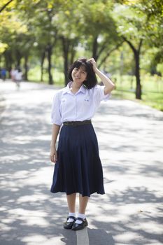 Asian female student Smiling and standing in the park.