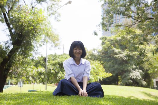 Girls relaxing on the lawn. Within the park with trees and greenery.