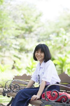 Girl sitting on the bench. Sitting and smiling happily in the park.