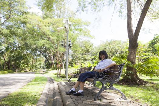 Girl sitting on the bench. Sitting and smiling happily in the park.