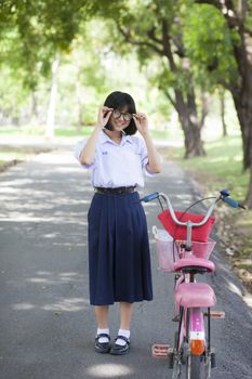 girl smile and relax Standing on the walkway in the park. There is a shady tree