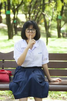 Woman told to keep quiet. Young woman sitting on a bench in the park.