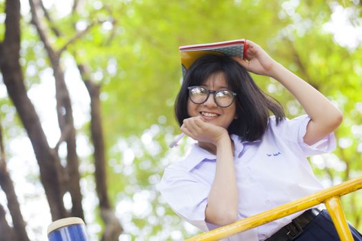 Schoolgirl smiling and happy. The books on head Relaxation time in the park.