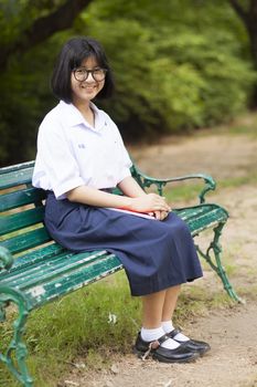 Schoolgirl. Sitting on the bench Smiling a happy in the park.