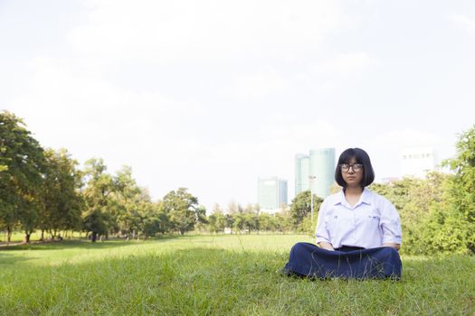 girl was meditating On the grass in the park. Girl wear glasses