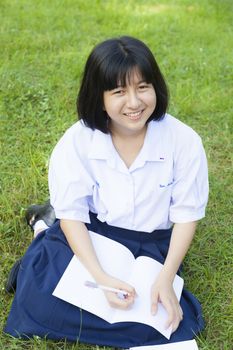 Girl reading on the lawn. Smiling a happy and enjoy. In a shady park