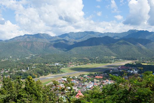 airport is at the foot of the mountain. High mountains near the airport. There is a village in the foothills and airport.