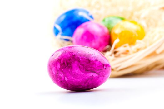 close up of colorful easter eggs in basket, on white background