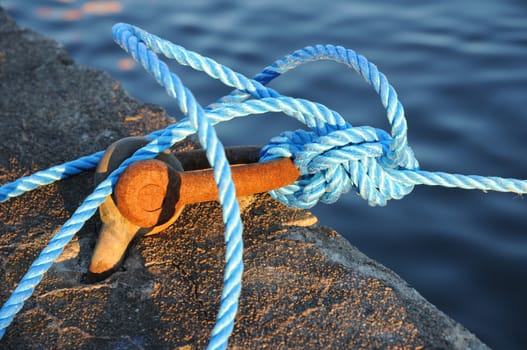 Rusty mooring with blue rope for securing a boat