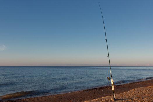 A fishing pole in sand by the sea