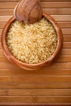golden rice on wooden plate on wooden background