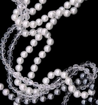 White, black and grey pearls on the black silk background 
