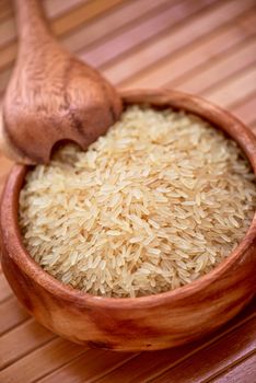 golden rice on wooden plate on wooden background