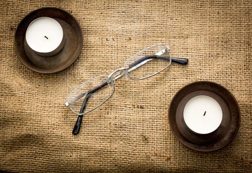 Two candles and reading glasses on a cloth