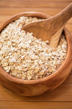 Oat flakes at wooden plate on wooden background