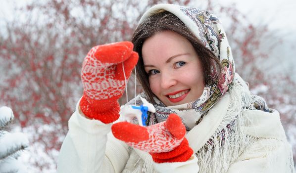 Beautiful young Russian folk woman in winter park with christmas tree toy