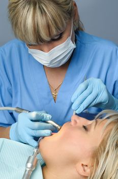 dentist at work with patient, using dental drill to cure the tooth