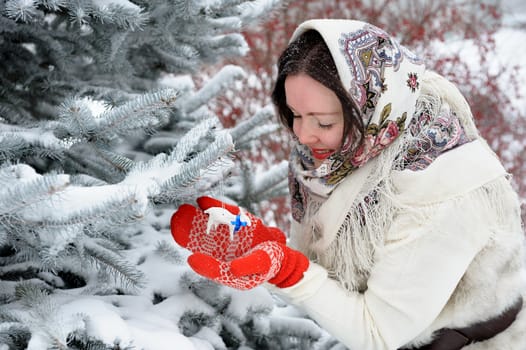 Beautiful young Russian folk woman in winter park with christmas tree toy