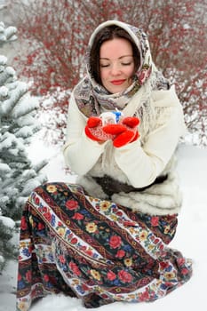 Beautiful young Russian folk woman in winter park with christmas tree toy
