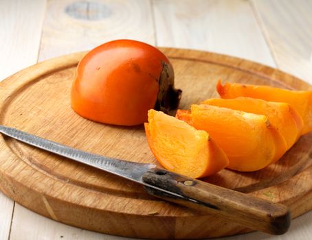 Tasty and ripe persimmon on wodden board
