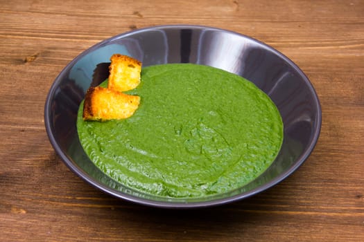 Creamed spinach with croutons on wooden table