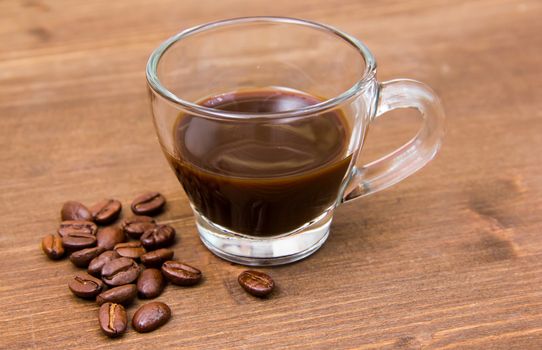 Cup of coffee and coffee beans on wooden table close up view