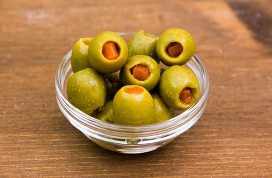 Stuffed olives in bowl on wooden table