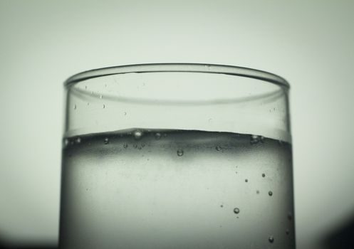 Glass of sparkling water soft drink closeup on carbon dioxide gas bubbles.